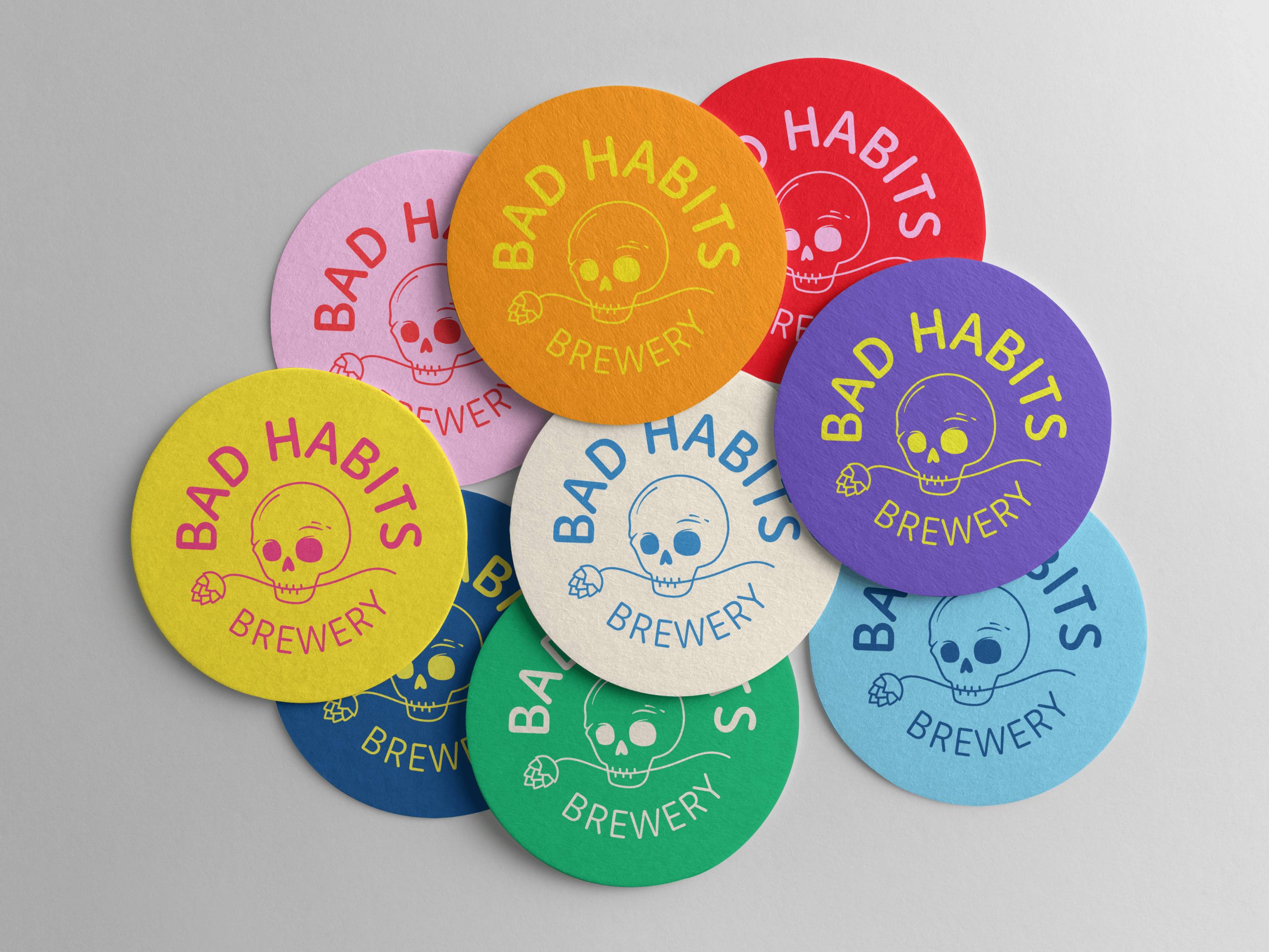Colorful round beer coasters featuring the Bad Habits Brewery logo with a playful skull and hop illustration, designed by Bruno de Aviz.